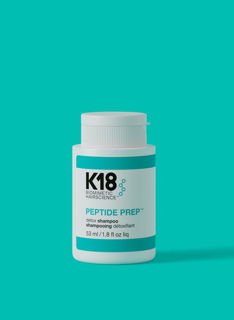 a-bottle-of-k18-peptide-prep-detox-shampoo-against-a-teal-background