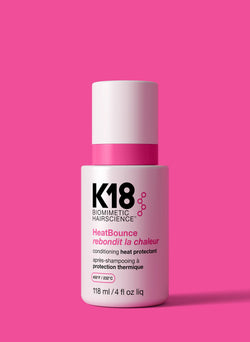 K18 HeatBounce conditioning heat protectant bottle on a pink background